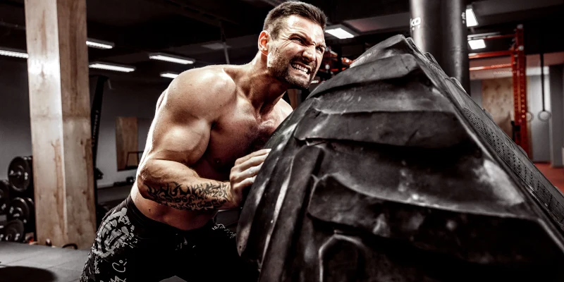 Man pushing tractor tire and getting back pain