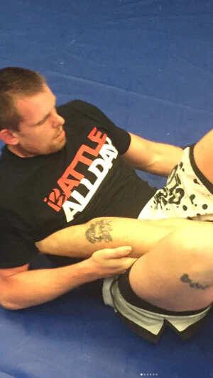 A mixed martial arts male practicing jiujitsu and wearing one of Battle Balm creative jerseys. This man loves Battle Balm all natural organic pain relief cream more than life itself.