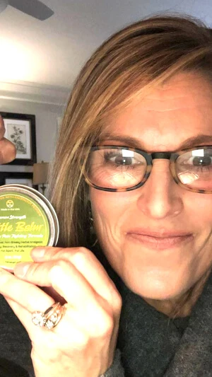 Instagram image of happy woman flexing & using Battle Balm demon strength topical pain cream for arthritis.