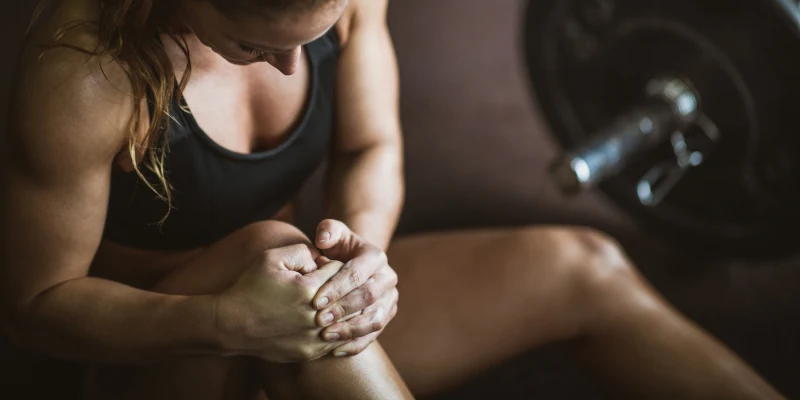 Female weightlifter holding knee pain