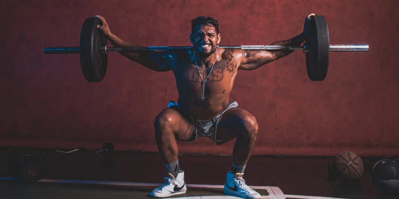 Man squatting with weights and has knee pain